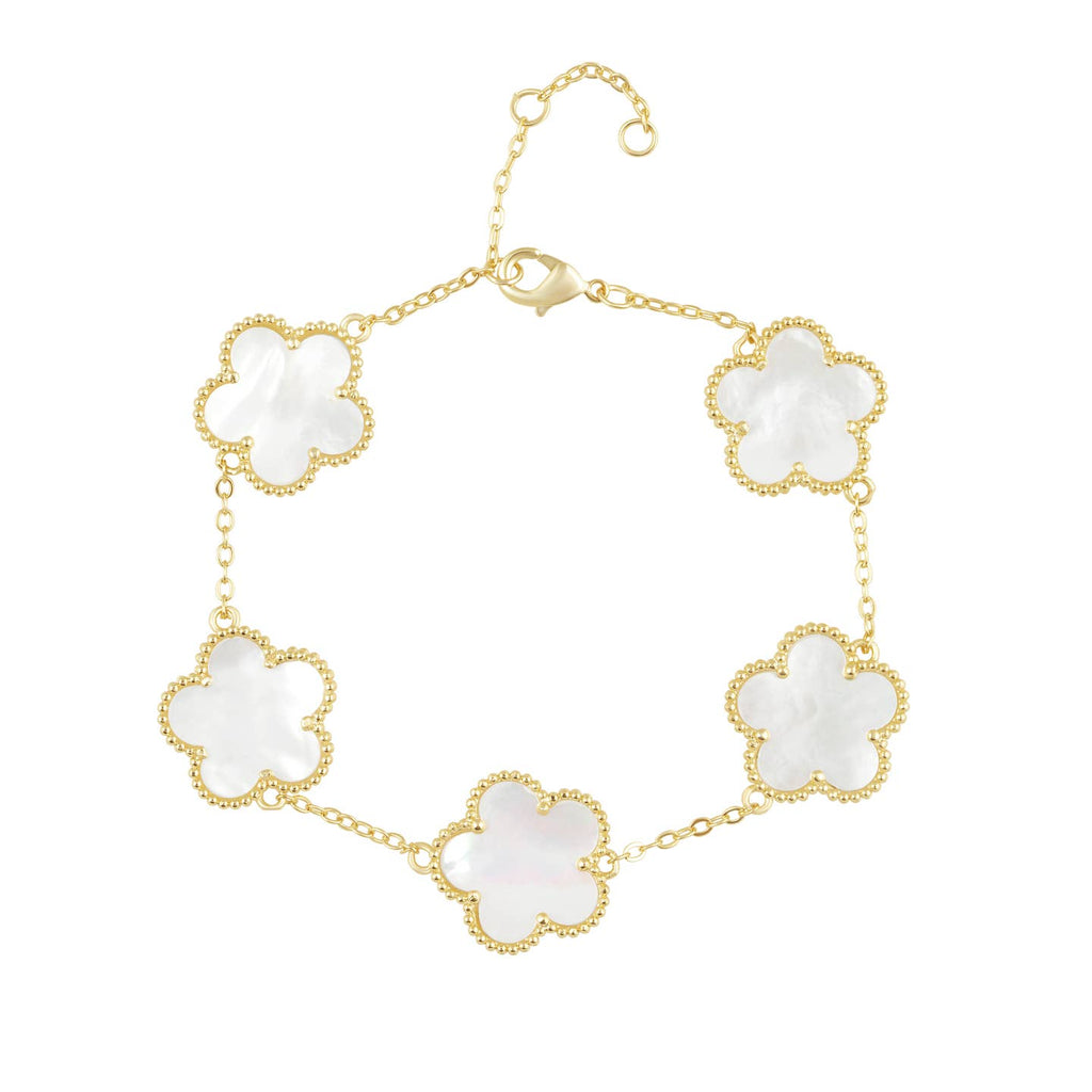 Gold bracelet with white flower-shaped links on a white background